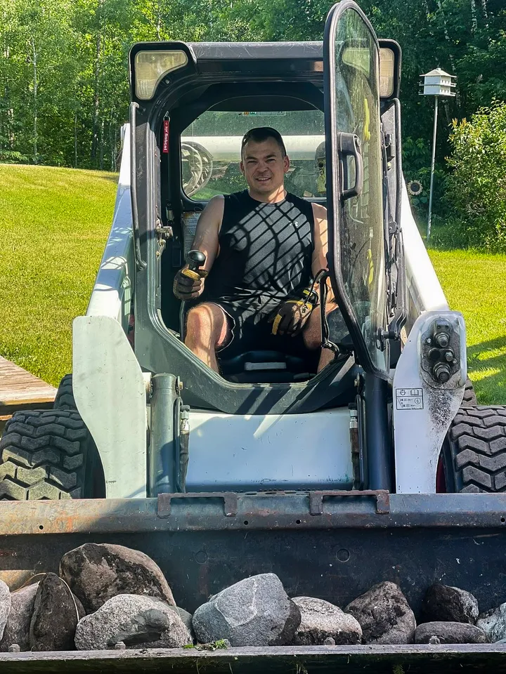 Chris Westlund in the seat of a Bobcat S650 skid steer, moving rock