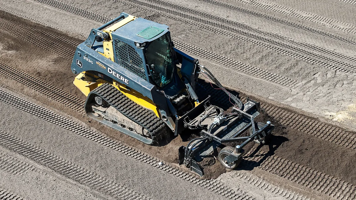 Aerial view of Shepard Excavating's John Deere 333G track loader pulling a power rake across a graded lot