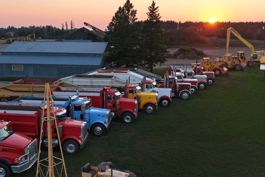 Storlie Construction equipment lined up in the yard at sunset